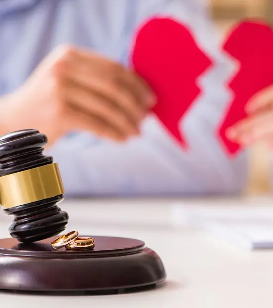 An image of a heatbroken couple facing divorce with rings and a gavel. 