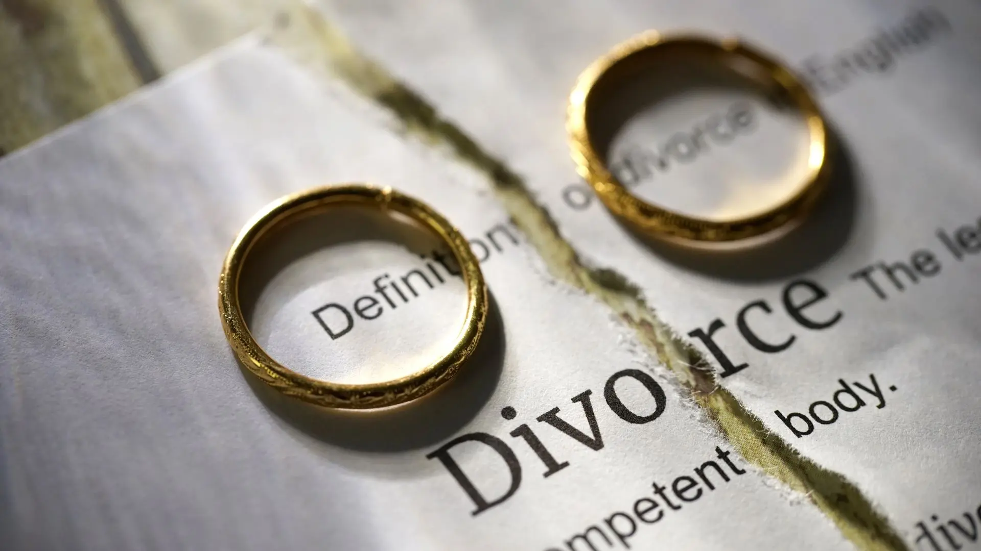 An image of two rings on a ripped divorce agreement paper.