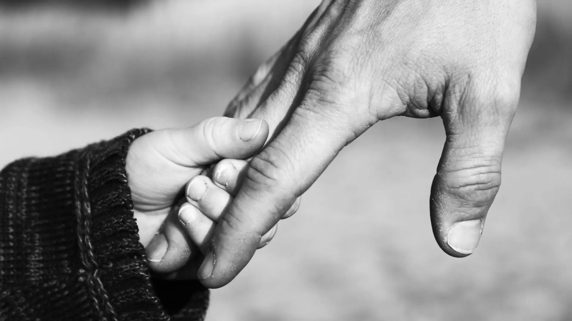 An image of a child holding their father's hand. 