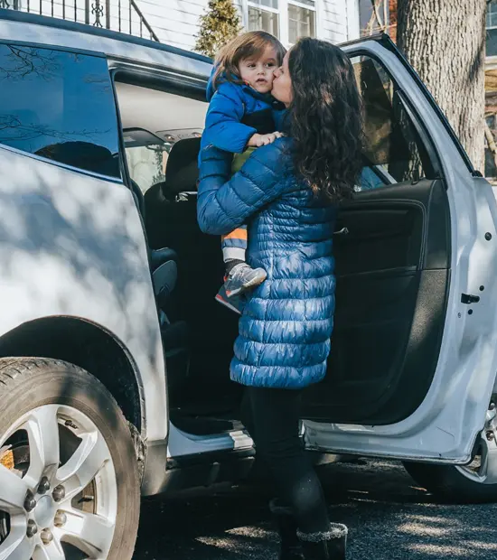 An image of a mother putting a child into a car to move away. 